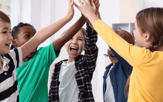 Group of kids high-fiving and smiling